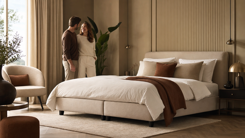Modernes Schlafzimmer mit grossem Boxspringbett in der richtigen Grösse – warmes natürliches Licht, aufgeräumte Atmosphäre