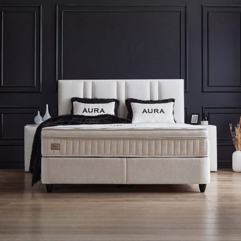 AURA Boxspringbett in Weiss mit Bouclé-Bezug, Frontansicht mit gepolstertem Kopfteil, Matratze und Topper vor dunkler Wandvertäfelung