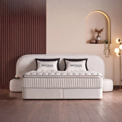 Brooklyn Boxspringbett in Samt Beige, Frontansicht im Schlafzimmer mit geschwungenem Kopfteil, Matratze und Topper