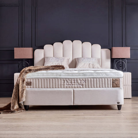 Jazzlyn Boxspringbett in Beige aus Samt, Frontansicht mit fächerförmigem Kopfteil, Matratze und Topper vor dunkler Wand