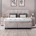 Lucia Boxspringbett in Grau-Beige aus Strukturstoff, Frontansicht im Schlafzimmer mit gepolstertem Kopfteil, Matratze und Topper