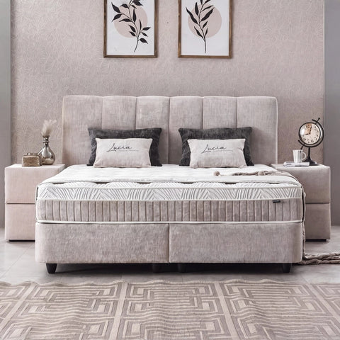 Lucia Boxspringbett in Grau-Beige aus Strukturstoff, Frontansicht im Schlafzimmer mit gepolstertem Kopfteil, Matratze und Topper