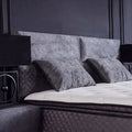 Detail vom gepolsterten Kopfteil des Babylon Boxspringbetts in Samt Grau mit Kissen und getufteter Matratzenkante