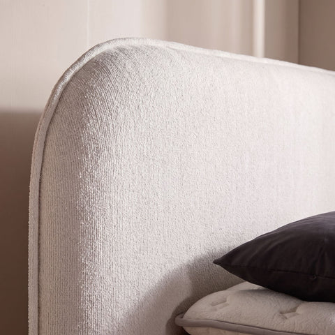 Nahaufnahme des beigen Bouclé Kopfteils des Brooklyn Boxspringbetts mit dunklem Kissen