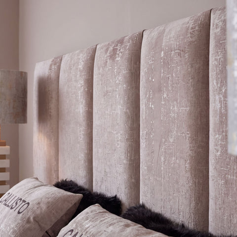 Nahaufnahme des beigen Samt Kopfteils mit vertikalen Polsterpaneelen und Vintage Textur
