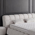 Detail vom gepolsterten Kopfteil des Claudi Boxspringbett in Bouclé Creme mit Kissen und orthopädischer Matratze