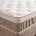 Nahaufnahme des weissen Toppers mit Knopfsteppung auf beigem Boxspringbett Sockel
