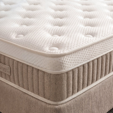 Nahaufnahme des weissen Toppers mit Knopfsteppung auf beigem Boxspringbett Sockel