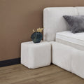 Esila Boxspringbett Creme, Detail vom Stoffbezug und passendem Nachttisch-Hocker in Würfelform neben dem Bett