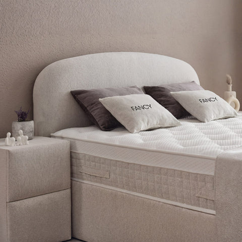 Detail vom gerundeten Kopfteil des Fancy Boxspringbetts in Samt Velours Beige, Matratze mit Topper und Fancy-Kissen im Nahblick