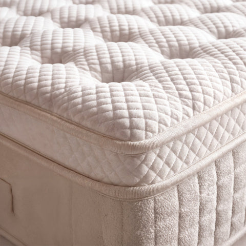 Nahaufnahme der gesteppten Topper Oberfläche und beiger Bouclé Verkleidung des Boxspringbetts