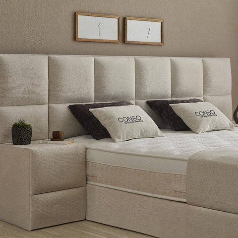 CONSO Boxspringbett Detail vom beigen Stoff-Kopfteil mit Kissen, Nahaufnahme von Bezug, Matratze und Topper
