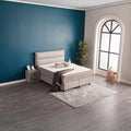 SUNA Boxspringbett mit Webstoff-Bezug Grau, seitliche Raumszene mit Kopfteil und Bettkasten vor blauer Wand