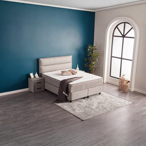 SUNA Boxspringbett mit Webstoff-Bezug Grau, seitliche Raumszene mit Kopfteil und Bettkasten vor blauer Wand
