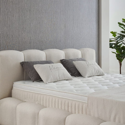 Detailaufnahme Kaona Boxspringbett – Teddy Bouclé in Beige, gestepptes Kopfteil, Matratze und graue Kissen