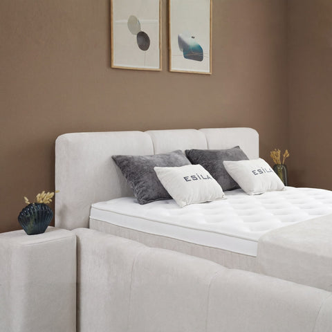 Esila Boxspringbett in Creme, Detailansicht vom gepolsterten Kopfteil mit Kissen und Topper im Stoffbezug