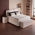 Phoenix Boxspringbett in Beige Bouclé, Schrägansicht mit Kopfteil, Matratze, Topper und Bettbank im warm beleuchteten Zimmer