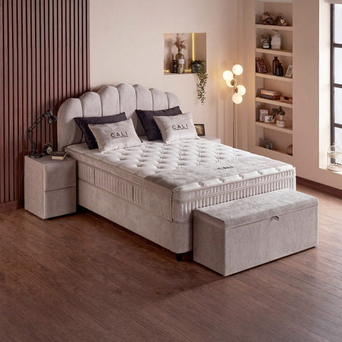 Cali Boxspringbett Samt Velours Beige in Seitenansicht mit Nachttisch, Bettkasten-Hocker und dickem Topper für Liegekomfort