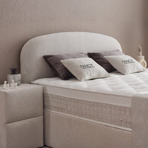 Detail vom gerundeten Kopfteil des Fancy Boxspringbetts in Samt Velours Beige, Matratze mit Topper und Fancy-Kissen im Nahblick
