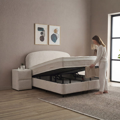 Fancy Boxspringbett Beige mit geöffnetem Bettkasten, Frau hebt Matratze an, viel Stauraum unter der Liegefläche in Samt Velours