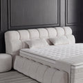 Detail vom gepolsterten Kopfteil des Claudi Boxspringbett in Bouclé Creme mit Kissen und orthopädischer Matratze