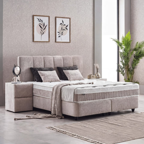Lucia Boxspringbett Grau-Beige in seitlicher Schlafzimmer-Szene, Strukturstoff-Bezug mit Kopfteil, Matratze und Nachttisch