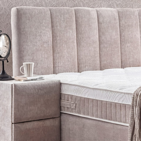 Detail vom gepolsterten Kopfteil des Lucia Boxspringbetts aus Strukturstoff in Grau-Beige mit Matratzenrand und Nachttisch