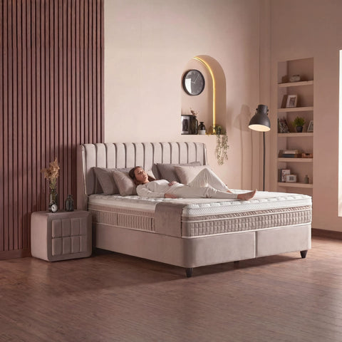 Bristol Boxspringbett Samt Beige im Schlafzimmer, Person liegt auf der Matratze und zeigt den Liegekomfort mit Topper