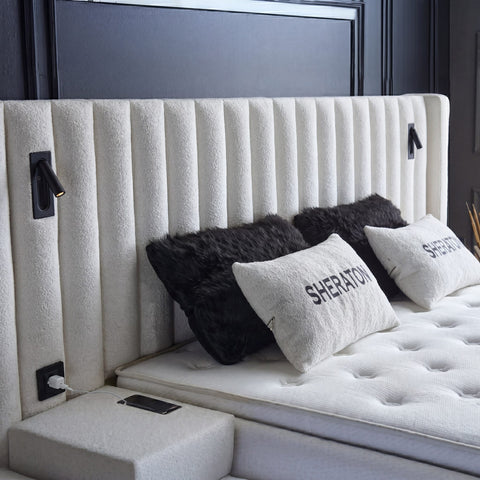 Kopfteil-Detail des Sheraton Boxspringbetts in Bouclé Weiss mit vertikaler Steppung, integrierten Leselampen und Kissen