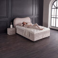Sofia Boxspringbett Teddy Beige mit Person auf der Matratze, Liegekomfort und Topper in stilvollem Schlafzimmer