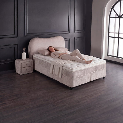 Sofia Boxspringbett Teddy Beige mit Person auf der Matratze, Liegekomfort und Topper in stilvollem Schlafzimmer
