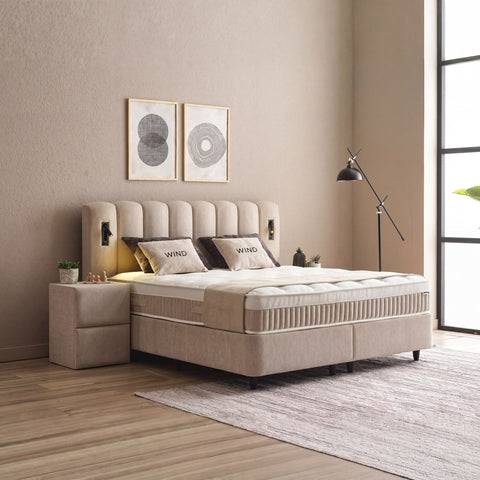 Wind Boxspringbett in Beige, seitliche Ansicht mit Stoffbezug, Kopfteil und Nachttisch im hellen Schlafzimmer