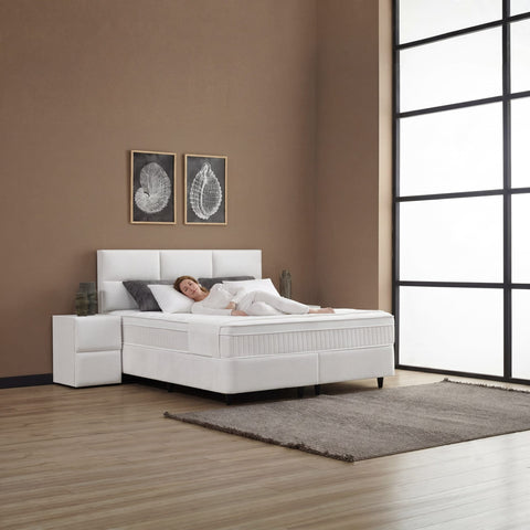 ZENZA Boxspringbett Stoff Creme in Schlafzimmer-Szene, Person liegend auf Matratze zeigt Liegekomfort mit Kopfteil